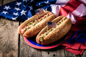 Foto del 4 de julio con perros calientes y una bandera estadounidense