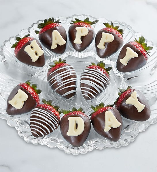 A photo of birthday gift ideas with a plate of chocolate covered strawberries with lettering on them.